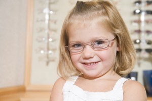 Young girl trying on eyeglasses at optometrists smiling